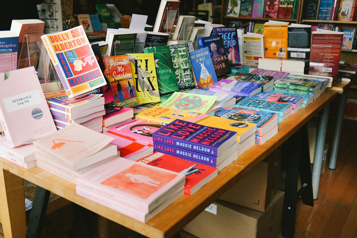 Stacks of new books displayed on a wooden table.