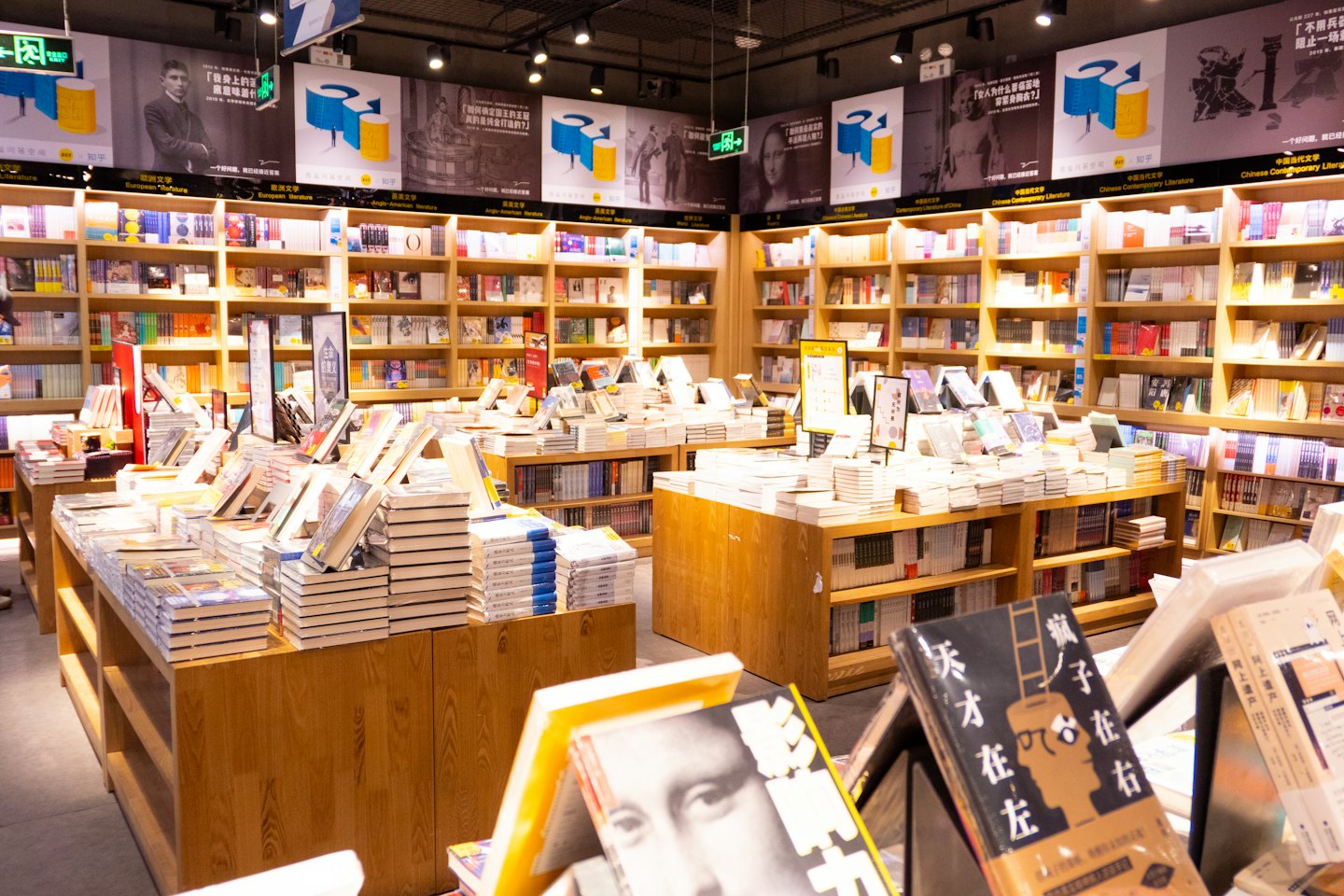 Modern bookstore with light wood shelves filled with books.