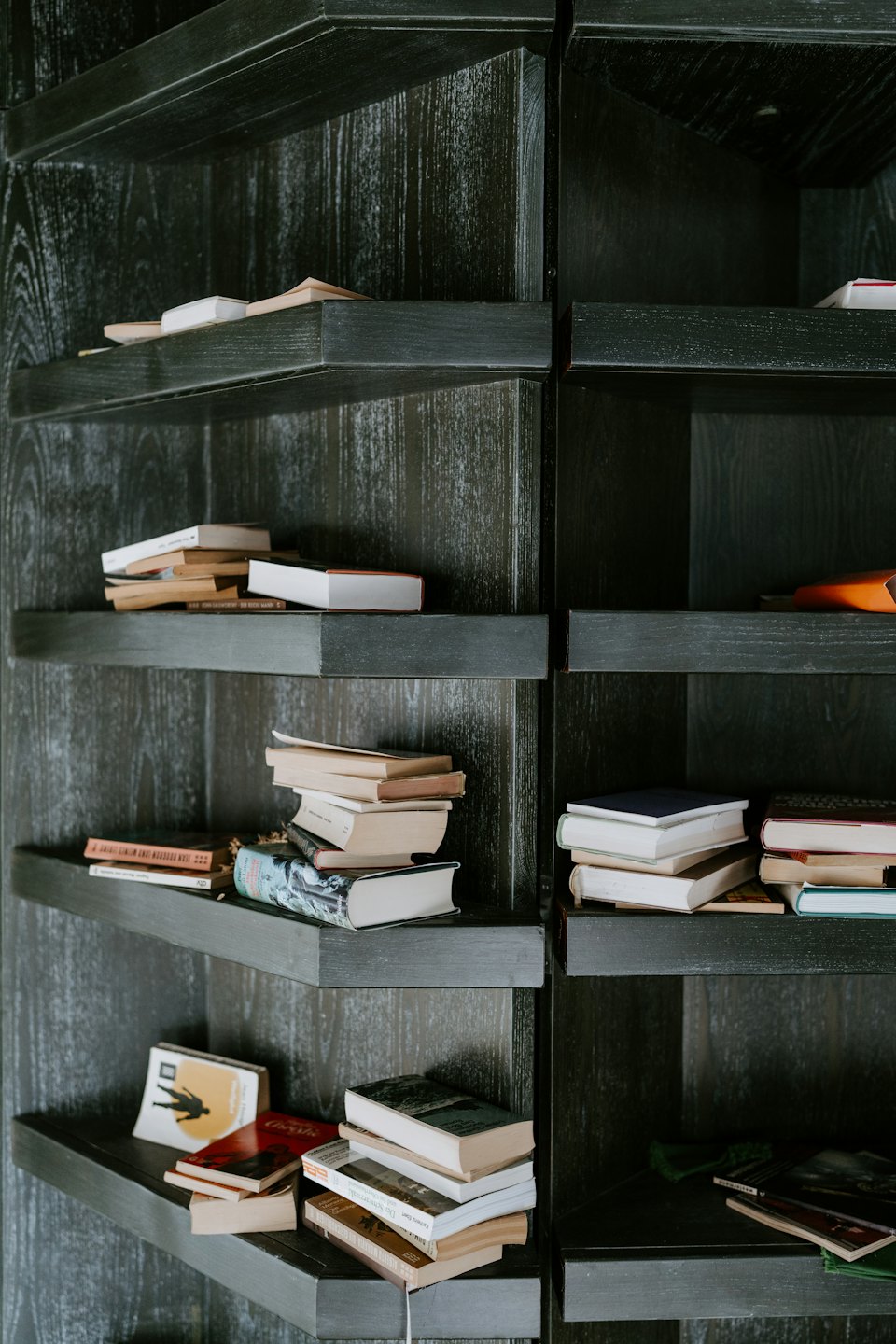 Wooden bookshelf filled with stacks of diverse books.