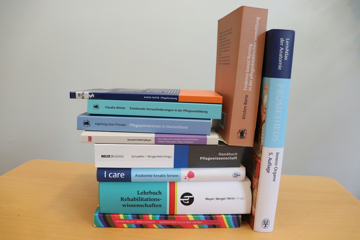 Stack of German and English academic textbooks on a wooden table.