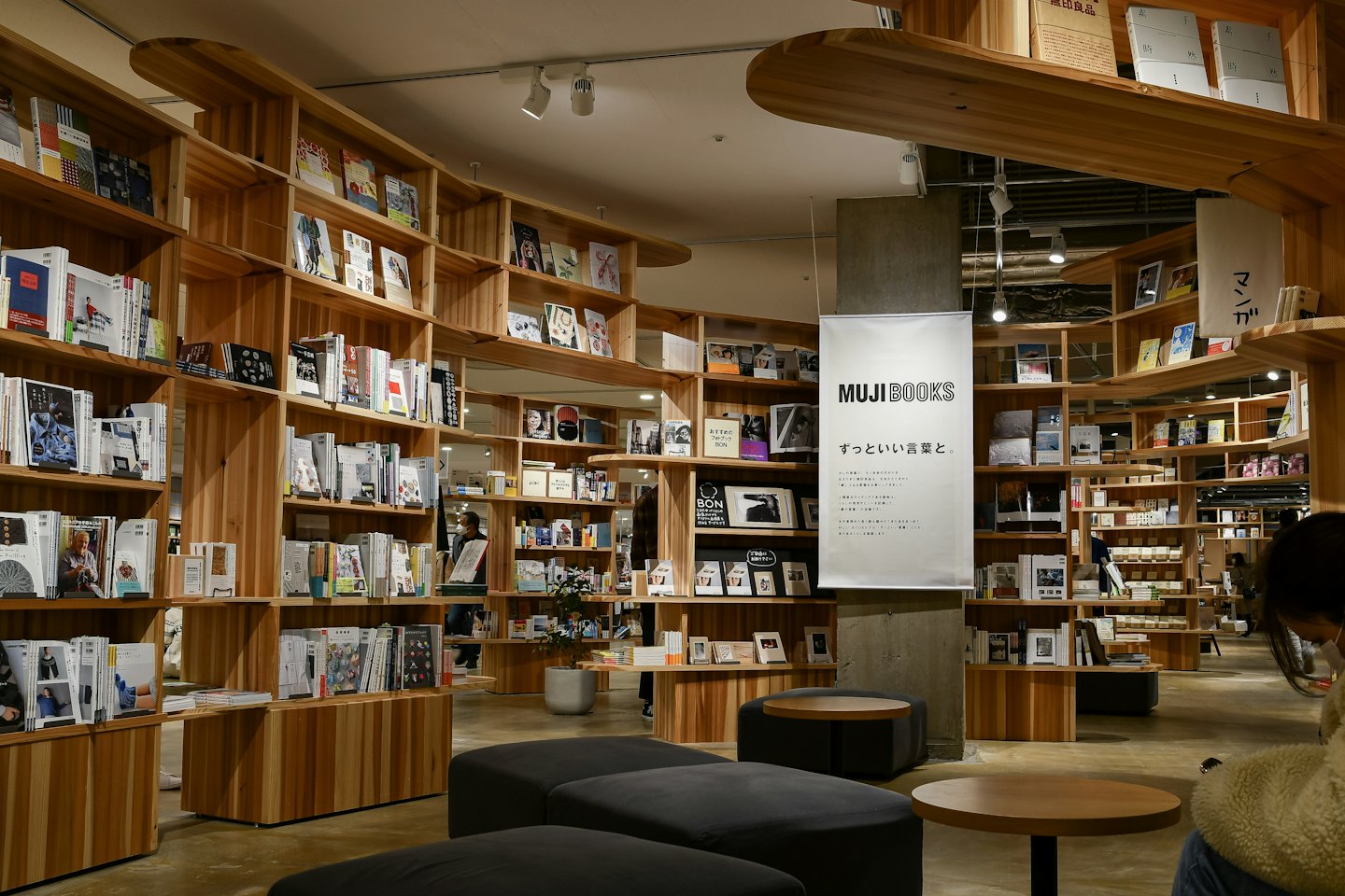 People browse bookshelves inside a modern store with hanging banners.